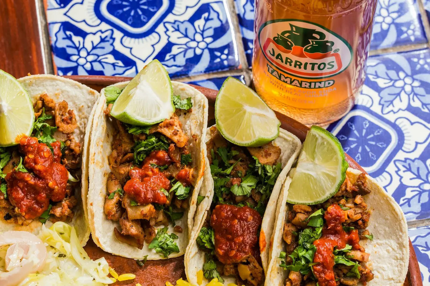 Four tacos with lime on a tiled table
